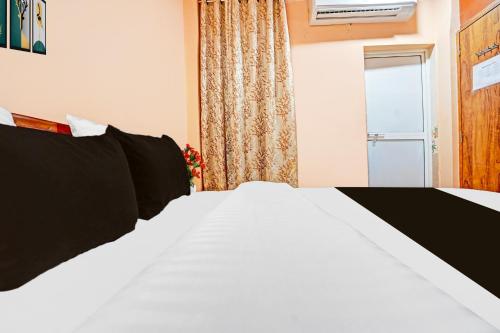 a white bed with black pillows in a room at Super Hotel O Dighori Nagpur in Sakardarā