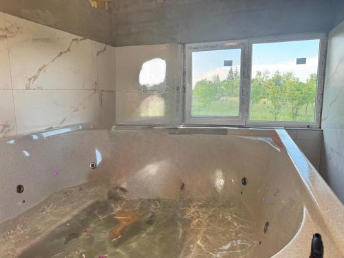 a bath tub in a room with two windows at Cabana Codrii Apusenilor - Matis in Râșca