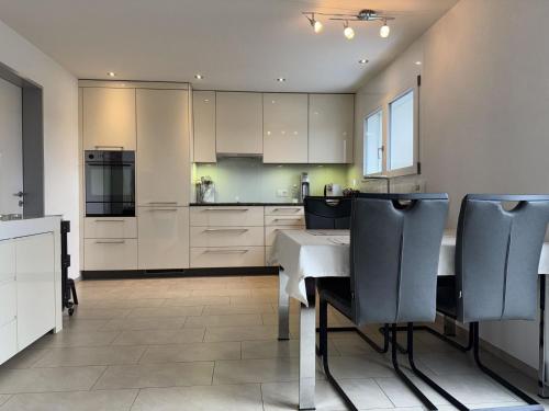 a kitchen with white cabinets and a table and chairs at Apartment Luxenweid by Interhome in Reichenburg