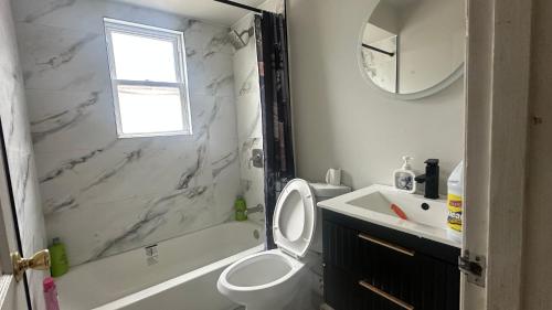 a bathroom with a toilet and a tub and a sink at Comfortable Private Room Shared Bathroom in Vinita Park