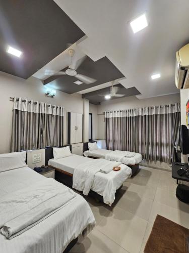 a hotel room with three beds and a tv at Hotel Royal Residency Executive in Miraj