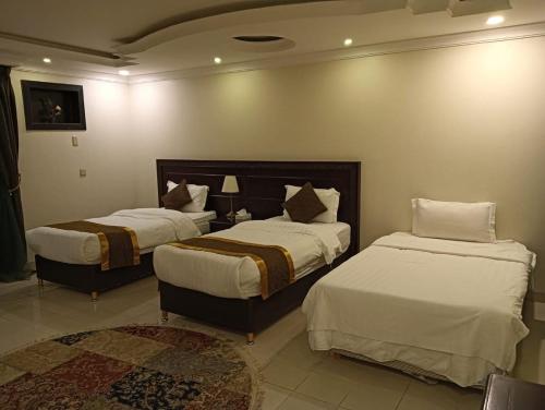 a bedroom with two beds and a rug at Arrawiya Alzahabia Hotel in Dammam