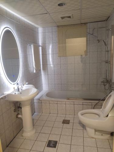 a bathroom with a sink and a toilet and a tub at Arrawiya Alzahabia Hotel in Dammam