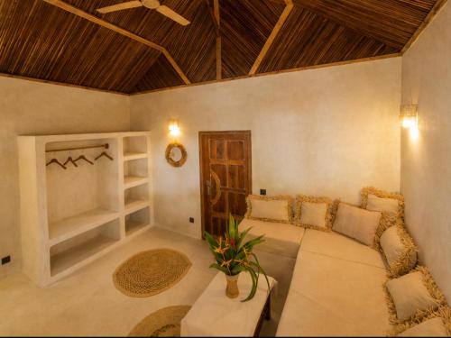 a living room with a large bed and a wooden ceiling at Les Bungalows De Ja in Nosy Be