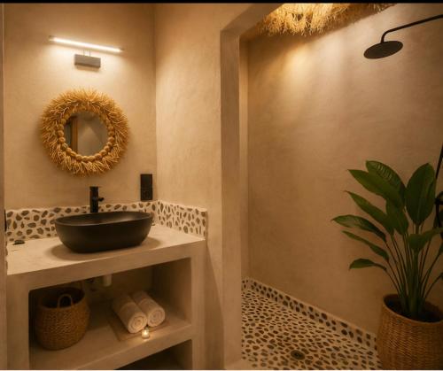 a bathroom with a sink and a potted plant at Les Bungalows De Ja in Nosy Be