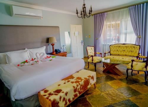 a bedroom with a large white bed and a chair at Kasimba Boutique Hotel in Gaborone