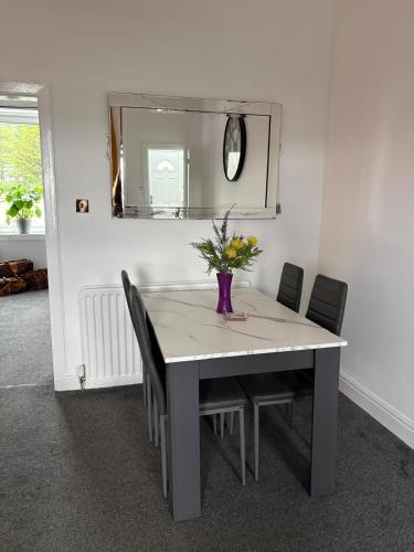 a dining room table with chairs and a vase with flowers at The M Rooms at 158 in Shotts Station