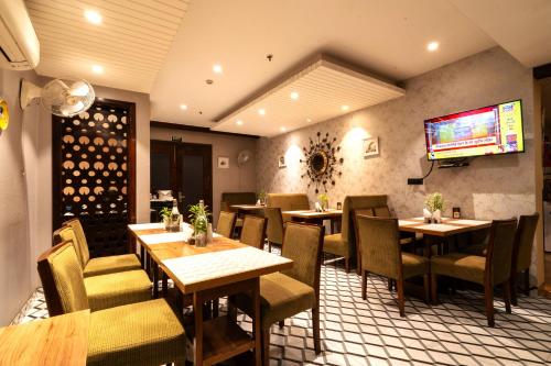 a restaurant with tables and chairs and a tv on the wall at Bluestone Nehru Place by The Cosy Hotels in New Delhi