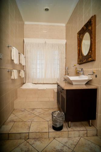 a bathroom with a tub and a sink and a bath tub at Kasimba Boutique Hotel in Gaborone