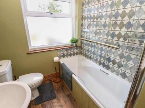 a bathroom with a tub and a toilet and a window at Banklands in Barnard Castle