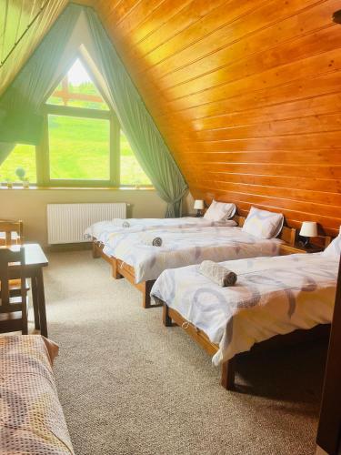 a row of beds in a room with a wooden ceiling at Chracowka in Małe Ciche