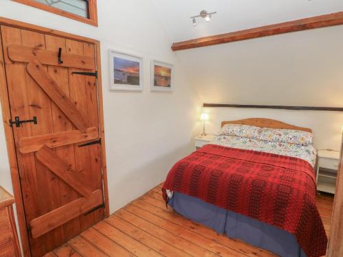 a bedroom with a bed and a wooden door at Penfeidr Newydd in Newport