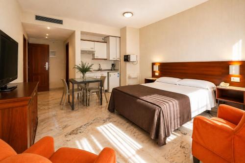a hotel room with a bed and a table and chairs at Apartamentos Vértice Bib Rambla in Seville