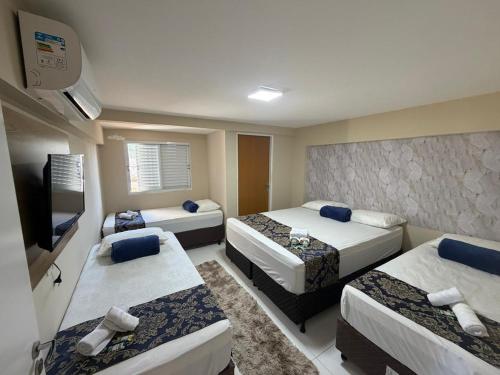 a hotel room with three beds and a flat screen tv at HOTEL LA SIERRA in Bodoquena