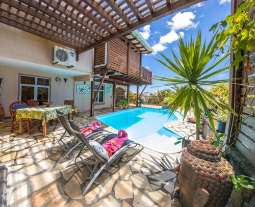 une terrasse avec une piscine, une table et des chaises dans l'établissement Blue Lagoon Villa, à La Gaulette