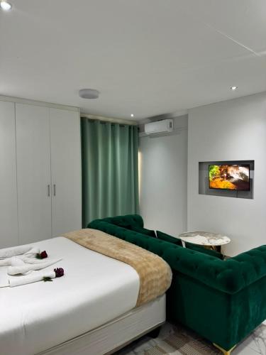 a bedroom with a large bed and a green couch at Malrose guesthouse Tours And safaris Windhoek Namibia Airport Shuttle services available in Windhoek