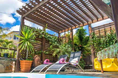 a pool with a wooden pergola and pink flamingos at Blue Lagoon Villa in La Gaulette