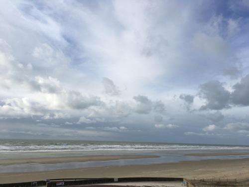 a beach with a cloudy sky and the ocean at Hotel La Terrasse in Fort-Mahon-Plage