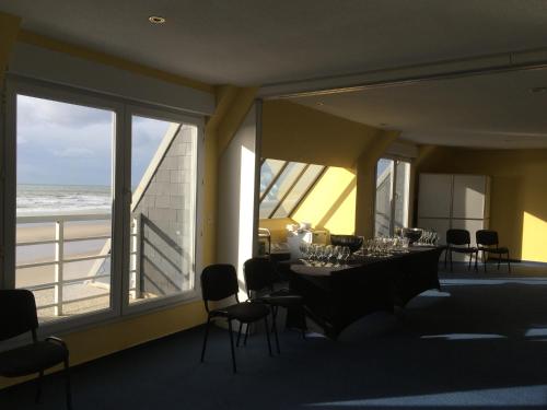 a dining room with a table and chairs and the ocean at Hotel La Terrasse in Fort-Mahon-Plage