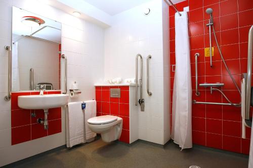 a red bathroom with a toilet and a sink at Travelodge Barcelona Fira in Hospitalet de Llobregat