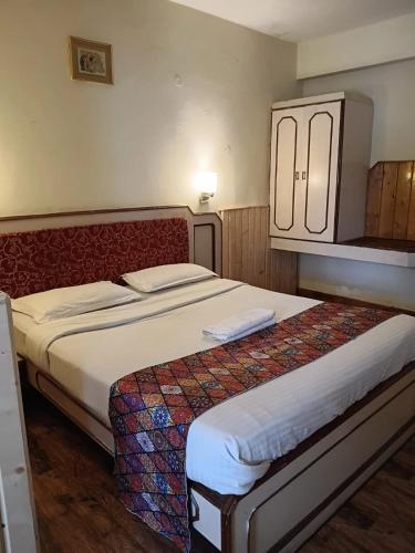 a bedroom with a large bed with white sheets at Hotel J'S Heritage in Kodaikānāl