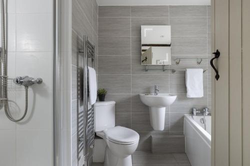 a white bathroom with a toilet and a sink at Perry Cottage in Halford