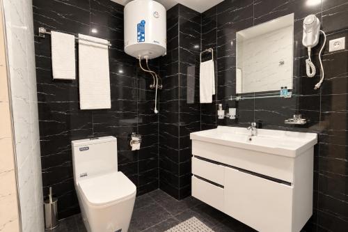 a black tiled bathroom with a toilet and a sink at Best One Hotel in Jizzax