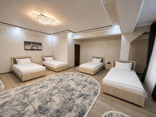a room with three beds and a rug at Best One Hotel in Jizzax