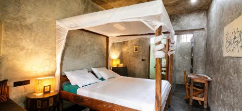 a bedroom with a canopy bed and a desk at BamBam Bungalows Zanzibar in Nungwi