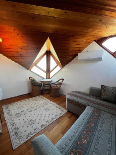 an attic room with a couch and chairs at Sziget Apartman Fonyód in Fonyód