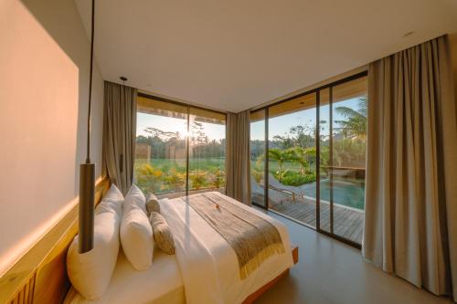 a bedroom with a bed and a large window at Casa Ariana in Ubud