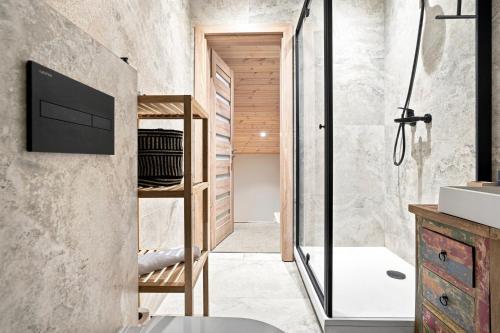 a bathroom with a walk in shower and a tv at Tago Forest - Dune Apartments in Jūrmalciems