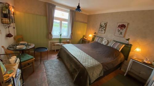 a bedroom with a bed and a table and a window at Gastenverblijf Buggenum Palace in Buggenum