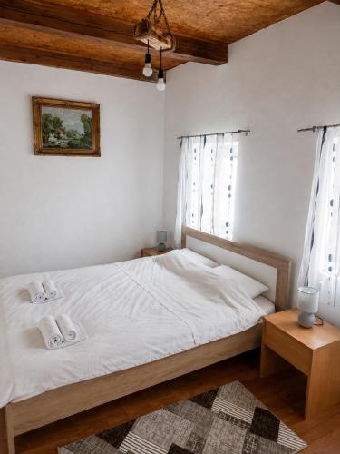 a bedroom with a bed with white sheets and windows at Stone house in Plužine