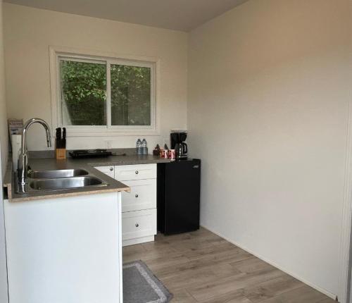 a kitchen with a sink and a black refrigerator at Chicken Shack Motel in Batchawana