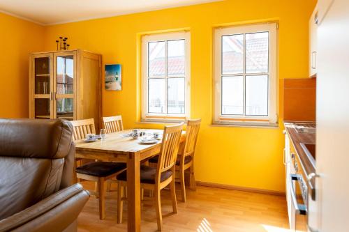 a dining room with yellow walls and a table and chairs at Gerlach in Zingst