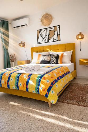 a bedroom with a large bed with colorful sheets and pillows at Le Rooftop Apparte - Barbecue, Grande Terrasse in Nabeul