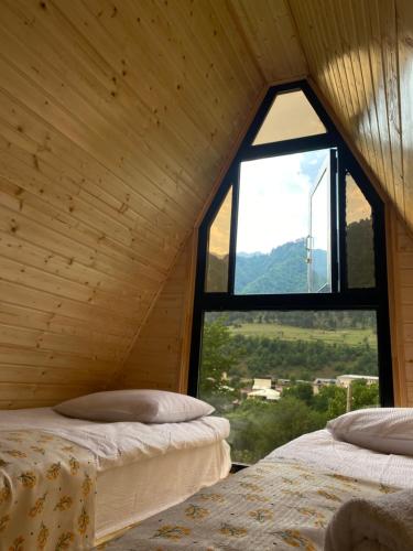 two beds in a room with a window at khedi cottage in Mestia