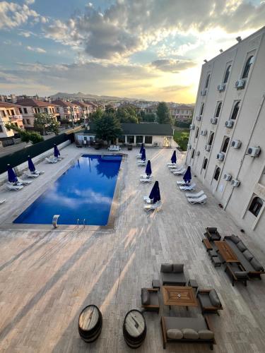 an outdoor pool with lounge chairs and tables on a building at Cappadocia Mihran Sultan in Avanos