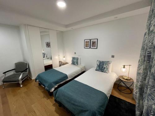 a bedroom with two beds and a chair at Carreira Residence in Funchal