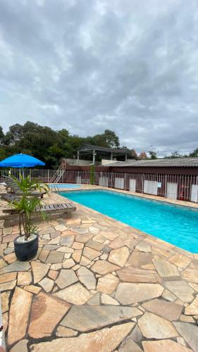 a swimming pool with a stone walkway and a blue pool at Hotel Beira Rio Guararema in Guararema