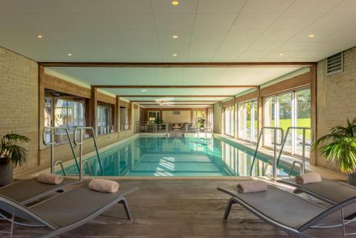 a swimming pool with two chairs in a building at Les Manoirs de Tourgéville in Deauville