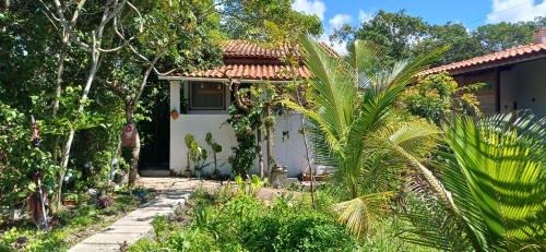 a small house in the middle of a garden at Casinha do Pedro próximo ao ponto do trator - Casinha branca in Ilha de Boipeba