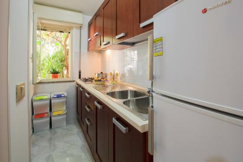 a kitchen with wooden cabinets and a stainless steel refrigerator at Hotel Village Eden in Capo Vaticano
