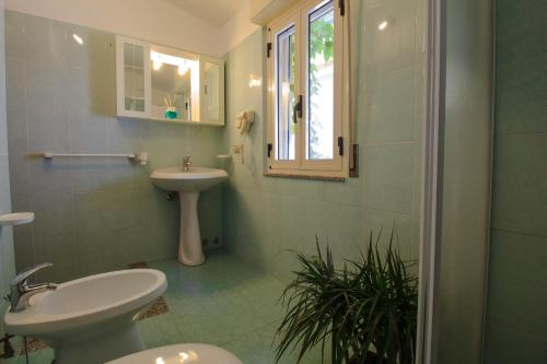 a bathroom with a sink and a toilet and a mirror at Hotel Village Eden in Capo Vaticano