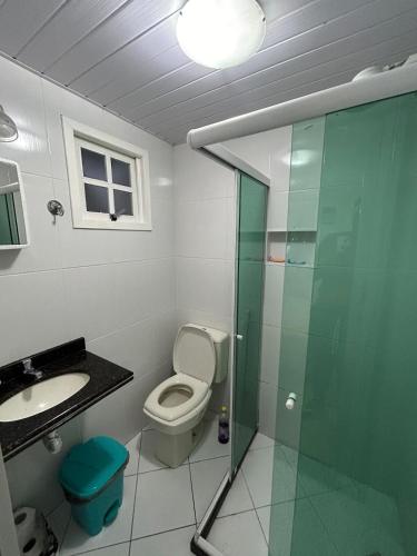 a bathroom with a toilet and a glass shower at Casas Arraial in Arraial do Cabo