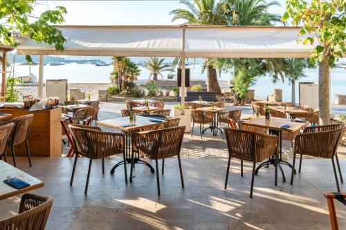 an outdoor restaurant with tables and chairs and the beach at Hotel Capri Pollensa in Port de Pollensa