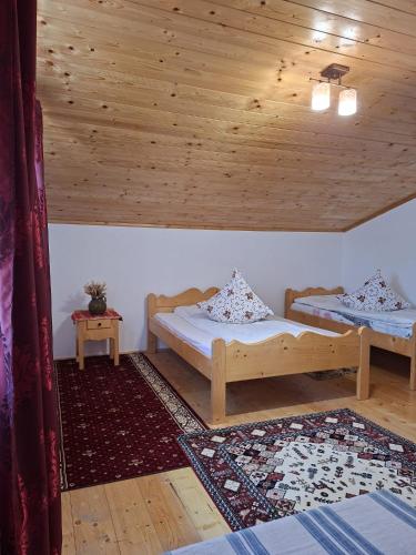 two beds in a room with a wooden ceiling at Cabana Codrii Apusenilor - Matis in Râșca