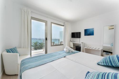 a white bedroom with a large bed and a window at Hotel Capri Pollensa in Port de Pollensa