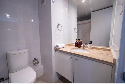 a white bathroom with a toilet and a sink at Suite moderna espacio parque in Calama